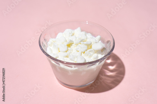 Cottage cheese in a glass container on a pink background