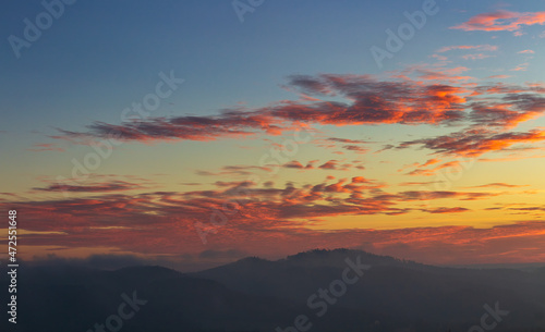 Distant hill in misty fog with amazing sunrise sky and cloud. Czech landscape
