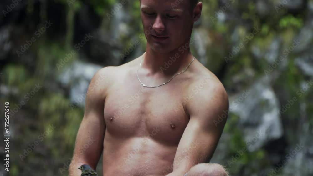 Small colorful bird eats out of young man's hand in forest, slow motion Small colorful bird eats out of young man's hand in forest, slow motion
