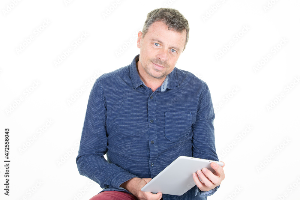 Happy middle aged man in casual blue shirt standing using tablet computer isolated over white background Happy middle aged man in casual blue shirt standing using tablet computer isolated over white background