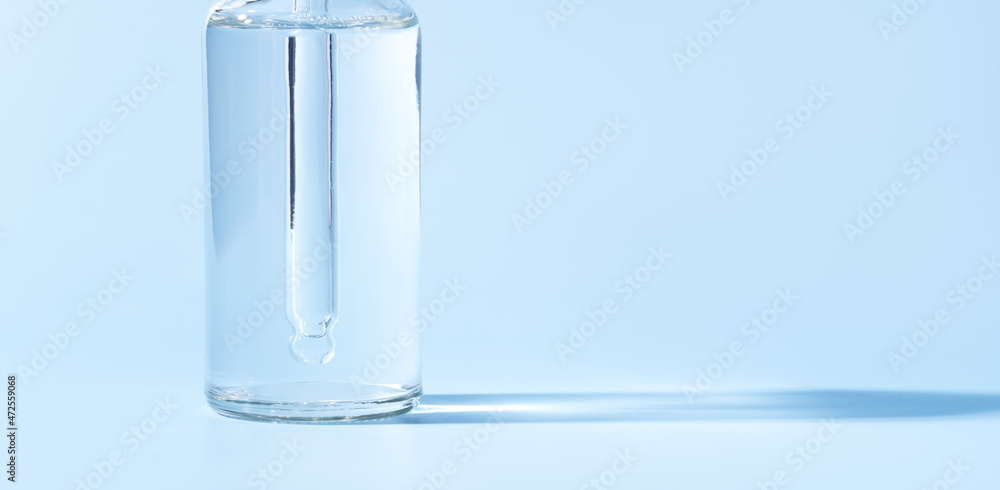 Glass jar with pipette of transparent liquid on blue background Glass jar with pipette of transparent liquid on blue background