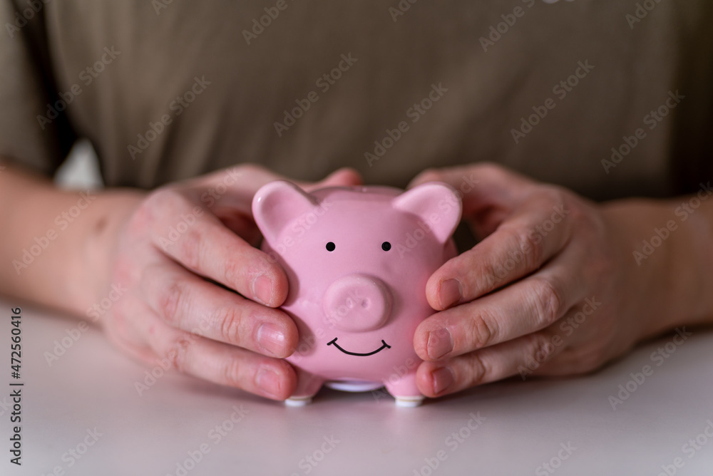 The businessman's hands hold a pink piggy bank. The businessman's hands hold a pink piggy bank.