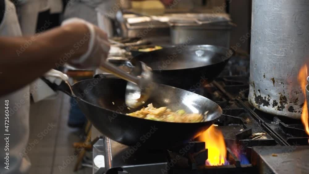 Chef flips and tosses fried rice in wok over flaming fire on commercial stovetop in restaurant kitchen, slowmotion HD Chef flips and tosses fried rice in wok over flaming fire on commercial stovetop in restaurant kitchen, slowmotion HD