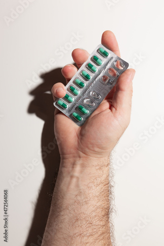 Wallpaper Mural Male hand holding blister pack with green capsules, medicine, on white background Torontodigital.ca