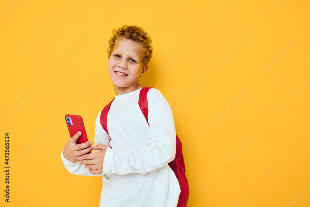 joyful schoolboy talking on the phone with a school backpack Studio learning concept joyful schoolboy talking on the phone with a school backpack Studio learning concept