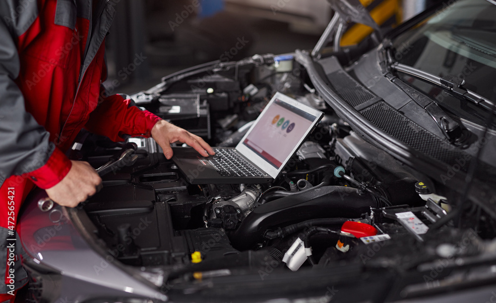 Crop mechanic using laptop during car diagnostics Crop mechanic using laptop during car diagnostics