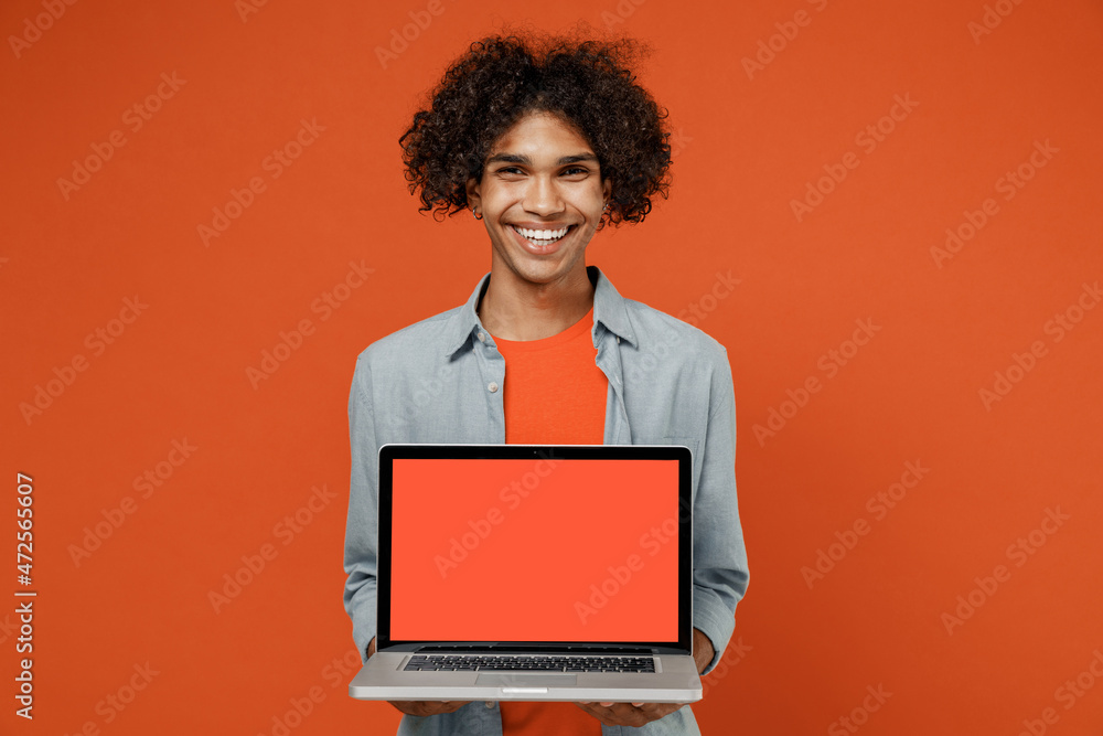 Young student black man 50s wearing blue shirt t-shirt hold use work on laptop pc computer browsing with blank screen workspace area isolated on plain orange color background People lifestyle concept Young student black man 50s wearing blue shirt t-shirt hold use work on laptop pc computer browsing with blank screen workspace area isolated on plain orange color background People lifestyle concept
