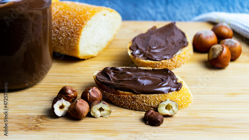 Chocolate spread on a piece of bread on a tree background. two slices of baguette with chocolate-nut paste.  a slice of baguette with chocolate-nut paste in a rustic style. Selective focus. 