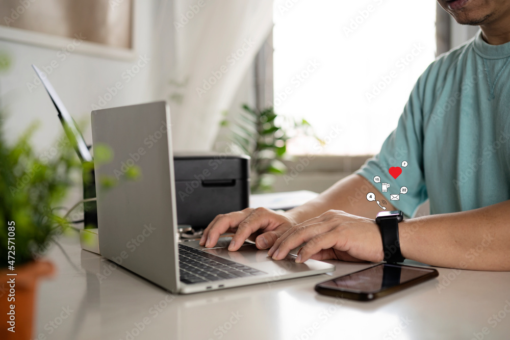 Businessmen sitting at his desk working with his laptop and smart watch alerts Businessmen sitting at his desk working with his laptop and smart watch alerts