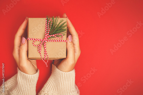 Christmas gift in women's hands on a red background