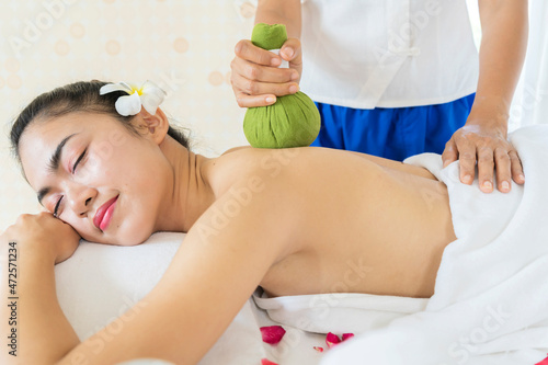 Young Asian woman is taking Thai Herbal ball hot compress massage in an authetic spa authentic photo