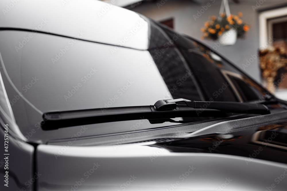 Close up of the windshield and wipers of a modern car. Automotive industry. Close up view of a pair of car wiper blades with small raindrops on window. - obrazy, fototapety, plakaty 