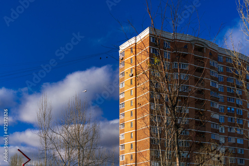 A helicopter and birds in the city sky next to a high brick house on an autumn day among the clouds in the blue sky. Safe flying concept photo