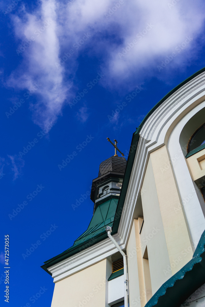 White clouds in the blue sky in contrast to the yellow-orange walls of the Christian temple in the rays of sunlight on an autumn day