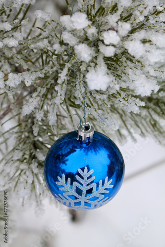 Blue glass ball among the snow-covered pine branches. Festive decoration. New Year. 