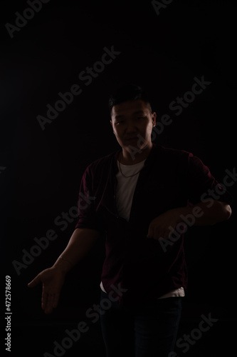 Asian man dancing to music in the dark at a disco