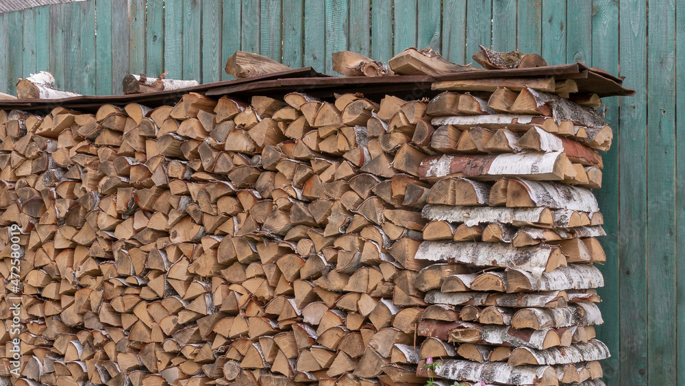 Firewoods stack at old fashioned wooden blue fence. Preparation for winter Firewoods stack at old fashioned wooden blue fence. Preparation for winter