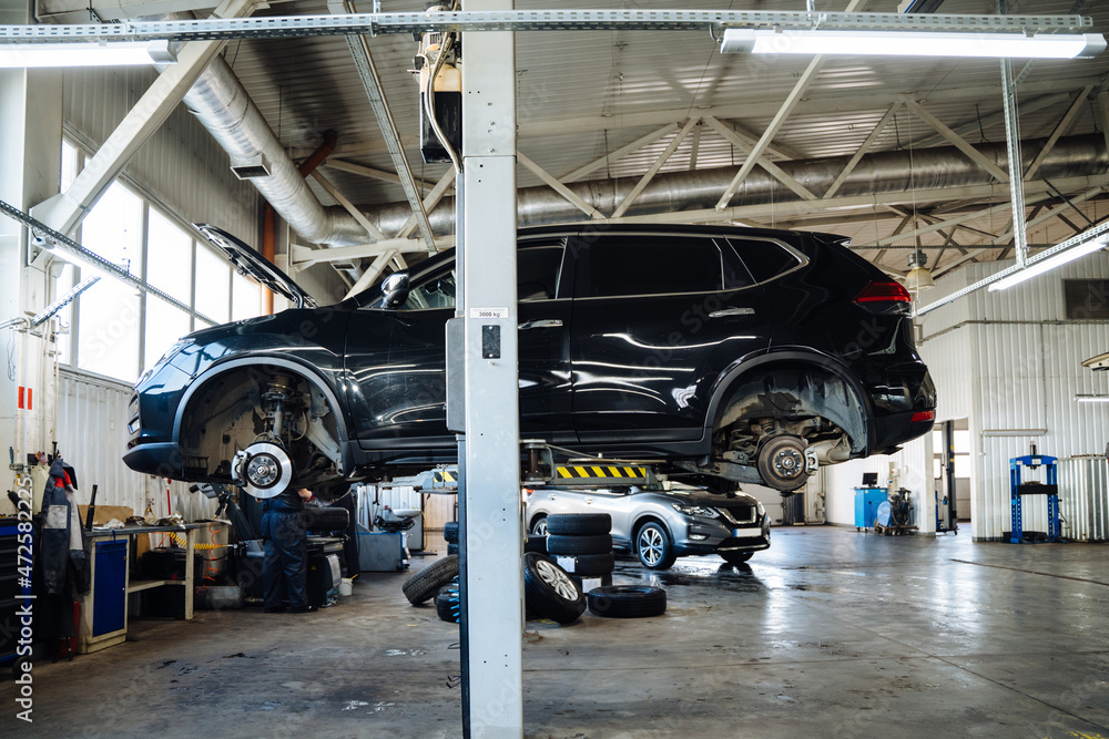 Fototapeta premium Car service, repair, maintenance concept. Car raised on car lift in autoservice.