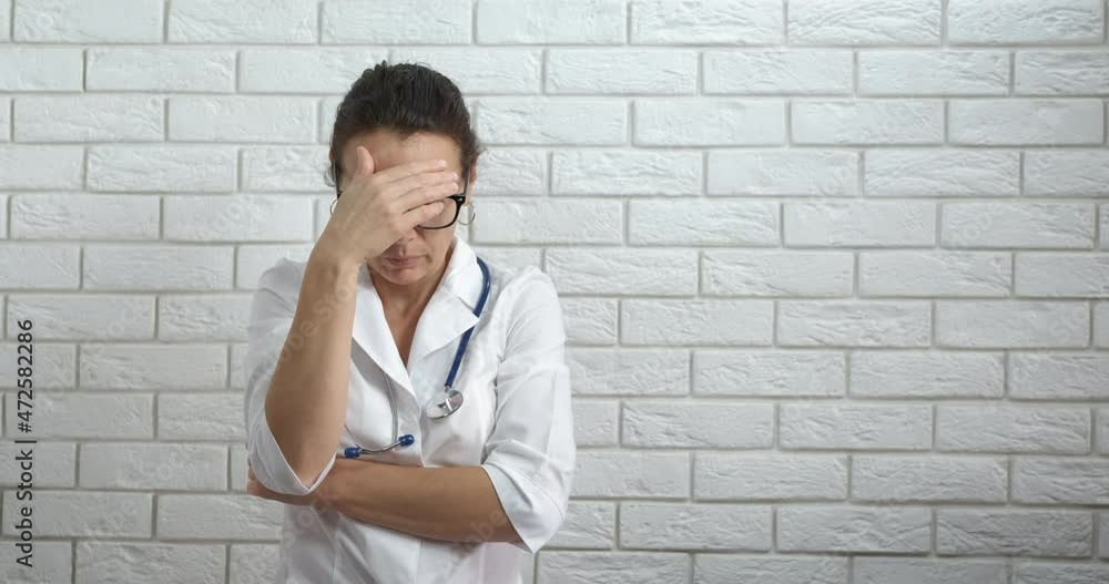 Stressed medical worker. A view of stressed medical worker stay in the room in sadness. Stressed medical worker. A view of stressed medical worker stay in the room in sadness.