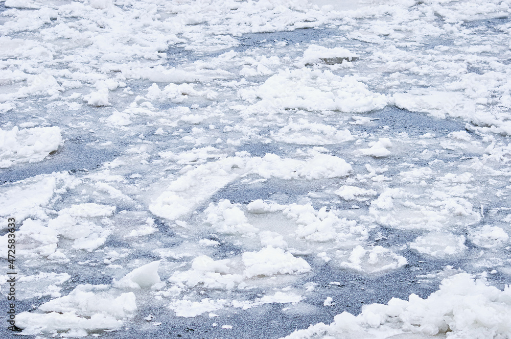 Snow-covered ice on the river during a snowfall. Winter texture. Suga and ice floes.