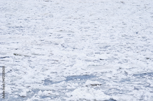 Snow-covered ice on the river during a snowfall. Winter texture.