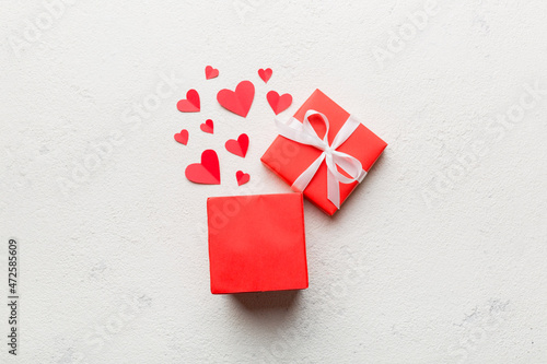 Happy valentines day opened heart shape gift box with small hearts, on colored background, valentines day card - top view concept