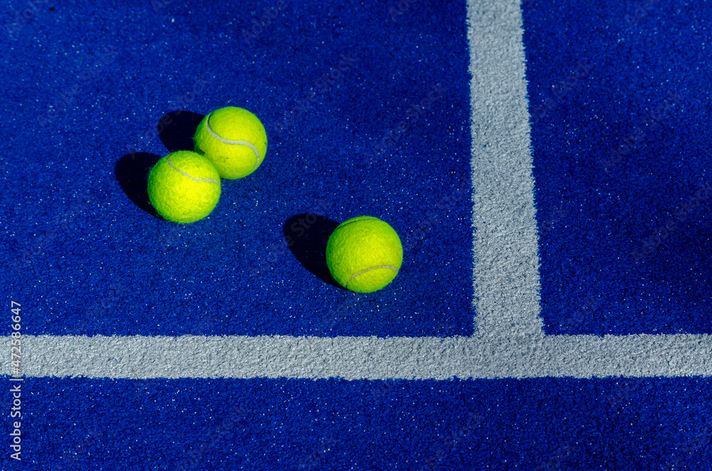 Three balls next to the lines in a paddle tennis court.