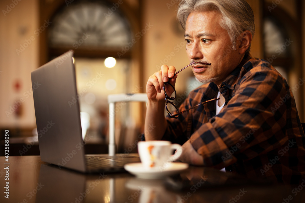 Businessman working on laptop in cafe. Handsome senior man enjoying in fresh coffee..