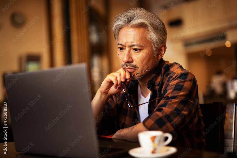 Businessman working on laptop in cafe. Handsome senior man enjoying in fresh coffee.. Businessman working on laptop in cafe. Handsome senior man enjoying in fresh coffee..