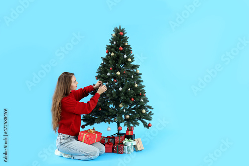 Attractive woman, Christmas tree and gift boxes on blue background