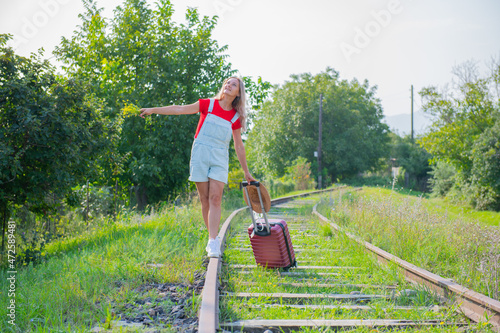 happy woman with hat walking on rails with suitcase © Vyacheslav