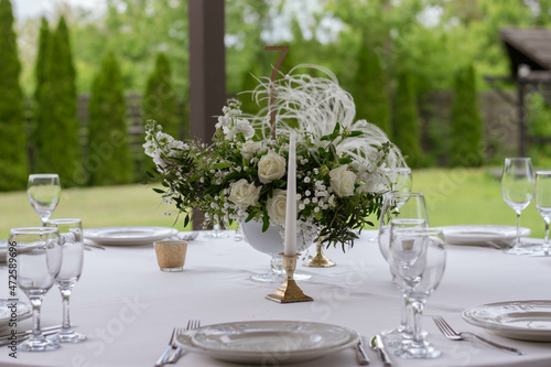 Table centerpiece with white and green floral arrangement in vase. photo