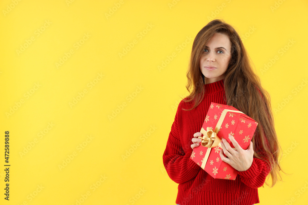 Attractive woman with Christmas gift box on yellow background Attractive woman with Christmas gift box on yellow background