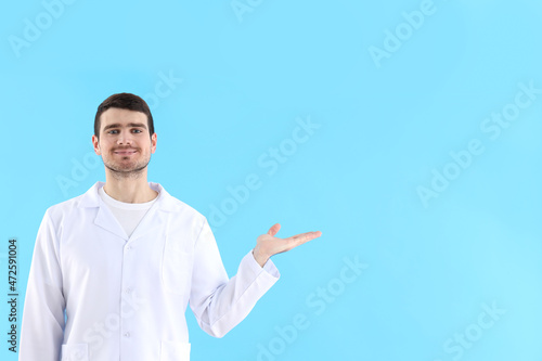Young man doctor on blue background, healthcare and medicine