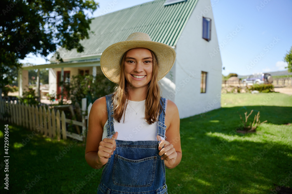 Smiling caucasian female farmer standing outdoors holding dungarees