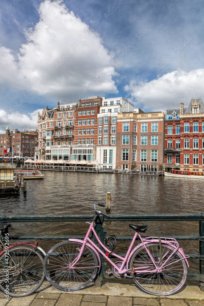 Fototapeta premium Amsterdam city with bikes against main canal during springtime in Netherlands.