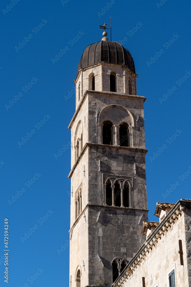 the Franciscan Church bell tower in the historic city center of Dubrovnik under a blue sky