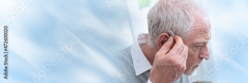 Man putting hearing aids; panoramic banner