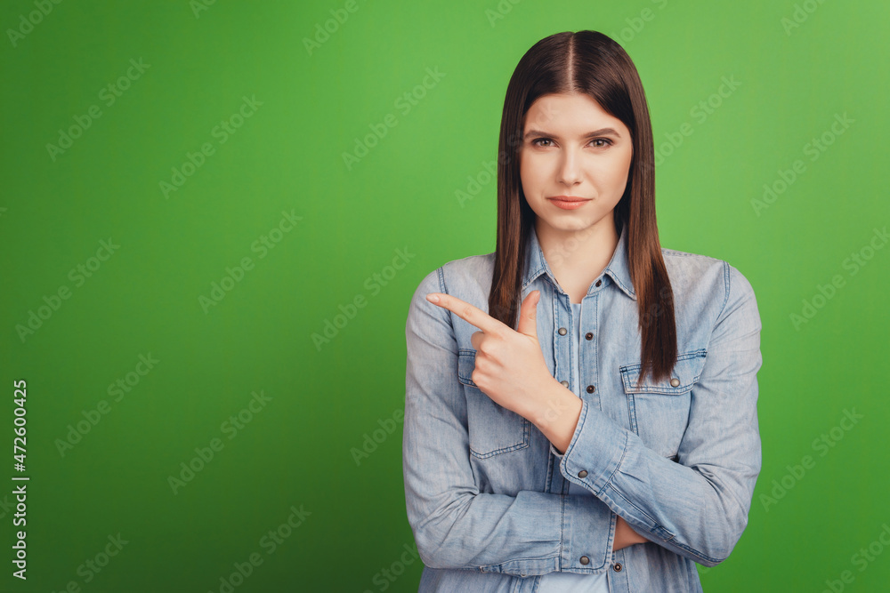 Photo of young attractive girl indicate finger empty space advertise decision isolated over green color background Photo of young attractive girl indicate finger empty space advertise decision isolated over green color background