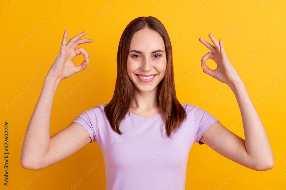 Photo of young pretty lady show fingers okey symbol quality excellent great isolated over yellow color background Photo of young pretty lady show fingers okey symbol quality excellent great isolated over yellow color background