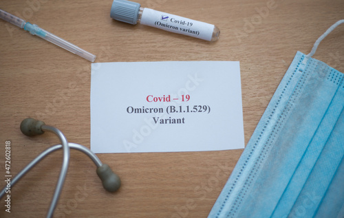 The new strain of Covid 19 variant called Omicron b.1.1.529 alarming concept on the office table. Top view of the new covid 19 variant text written on paper with medical equipment around displaying.  photo