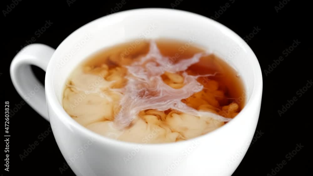 Tea with milk. Pour milk in tea, close up. 4K UHD video Tea with milk. Pour milk in tea, close up. 4K UHD video