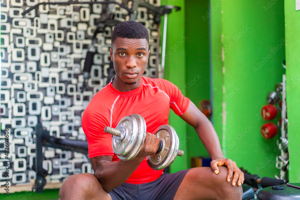 handsome power athletic man in training pumping up muscles with dumbbell handsome power athletic man in training pumping up muscles with dumbbell