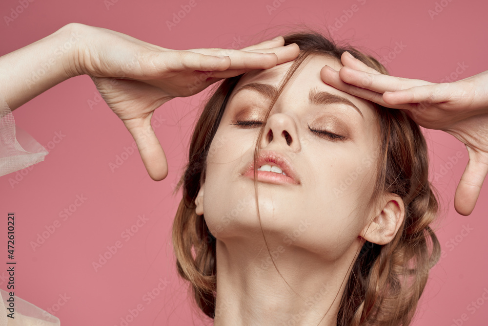 Fototapeta premium portrait of a woman gesture hands cosmetics fashion hairstyle posing pink background