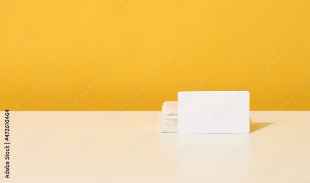 stack of white rectangular business cards on a yellow background, company branding, address. stack of white rectangular business cards on a yellow background, company branding, address.
