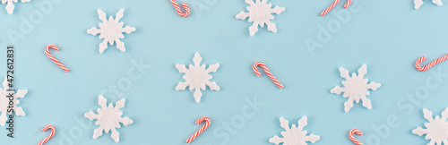 Christmas composition. Banner made of snowflakes, red and white candies on blue background. Christmas, winter, new year concept. Minimal style. Flat lay, top view