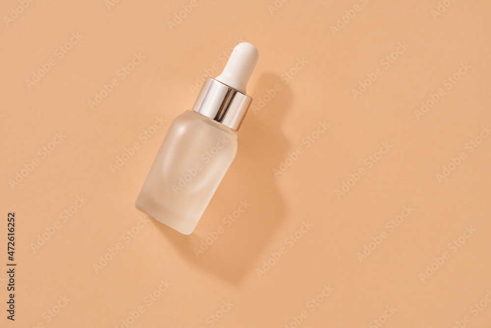 A bottle of essential oil on orange background, top view A bottle of essential oil on orange background, top view