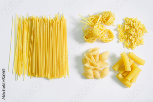 Italian spaghetti, farfalle, conciglioni, rigatoni and tagliatelle in groups on a white plate. Assorted. View from above