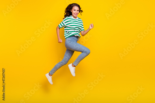 Full size profile side photo of young cheerful girl runner energetic speed jump isolated over yellow color background