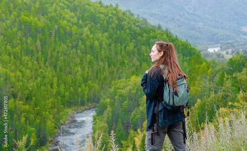 Young woman with backpack enjoys the view of nature at hike. Empty space for text